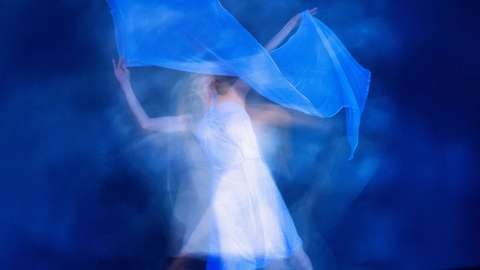 Valkoiseen pukeutunut henkilö tanssii huivin kanssa.