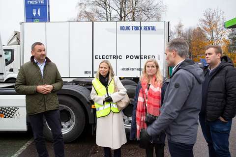 Viisi ihmistä keskustelemassa sähköisen kuorma-auton edessä