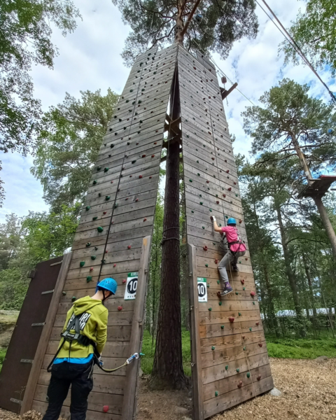 Nuorisonohjaaja ja nuori kiipeilemässä kiipeilyseinässä