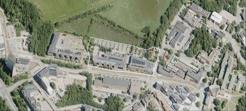 Flygbilden visar planområdet. I förgrunden längs Marvägen ligger de tre och fyra våningar höga högskolebyggnaderna. Bakom byggnaderna i planområdets norra del finns en stor parkeringsplats.