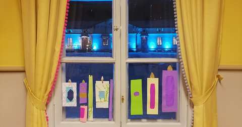 Talon ikkuna kuvattuna sisältä päin pihalle, ikkunassa itsetehdyt paperikynttilät.