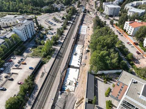 An aerial photo of the construction site at the Kilo railway station. The tracks are surrounded by trees and buildings.