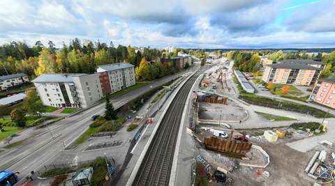 An aerial photo of the construction site at the Tuomarila railway station. Roads, buildings and trees surround the tracks.