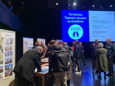 Ihmisiä keskustelemassa erilaisilla ständipisteillä.