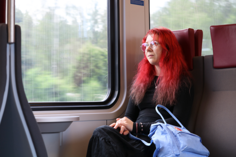 En person med rött hår sitter på ett närtåg.