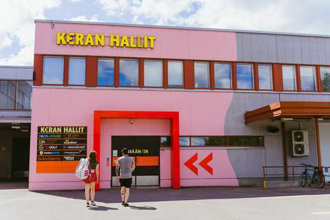 Kaksi henkilöä menossa sisään Keran Halleille. Ovien vieressä listataan hallien yrityksiä.