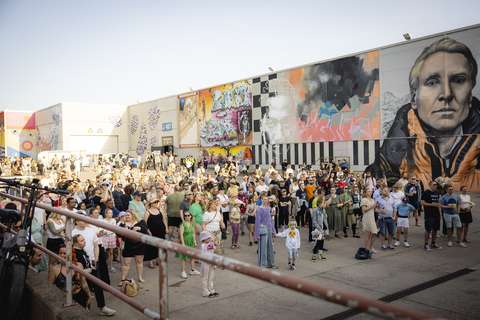 Ihmisjoukko muraalein koristellulla asfalttipihalla.