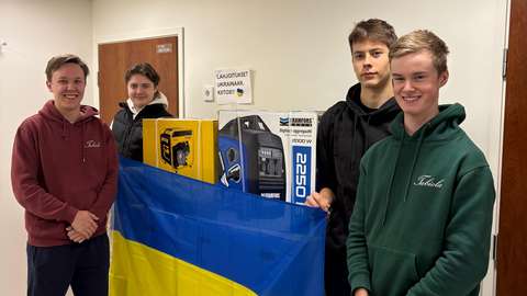 Neljä poikaa seisoo pöydän ympärillä, jota peittää Ukrainan lippu..