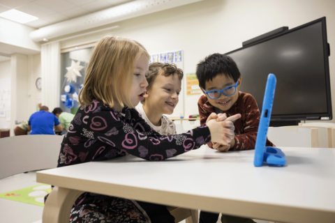 Kolme lasta tutkii tablettia animaatiotyöpajassa.
