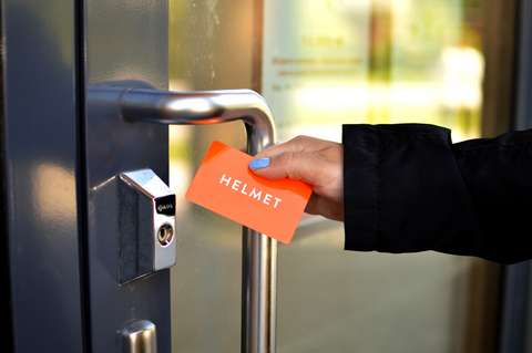 Käsi pitelee kirjastokorttia ja ovenkahvaa.