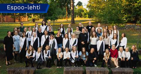 Noin 50 kuorolaista katsoo kohti kameraa, kuva on otettu ulkona.