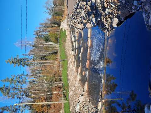 Vesireitillä on kivistä rakennettu kivikynnykset. Taustalla on puita ja sininen taivas.