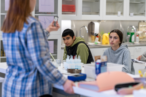 Kaksi oppilasta ja opettaja fysiikan oppitunnilla