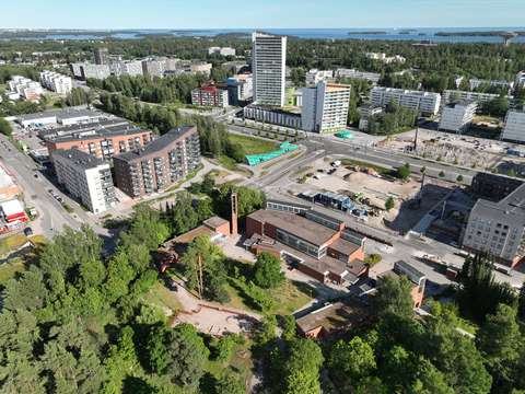 Ilmakuva, jossa näkyy puita, rakennuksia, rakennustyömaita ja teitä.