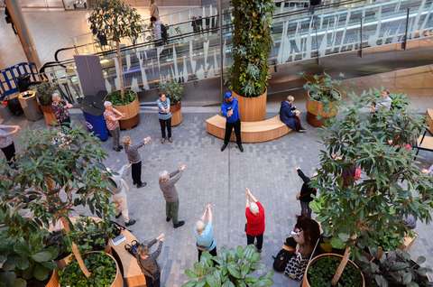 Ryhmä senioreita venyttelee kauppakeskuksen käytävällä.