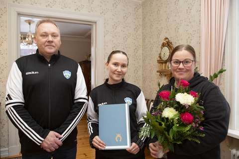 Kolme henkilöä Esbo Bollklubb ry:stä Gumbölen kartanolla, sylissä kukkakimppu ja todistus.