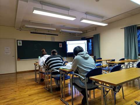 Kolme naista opiskelemassa luokkahuoneessa.