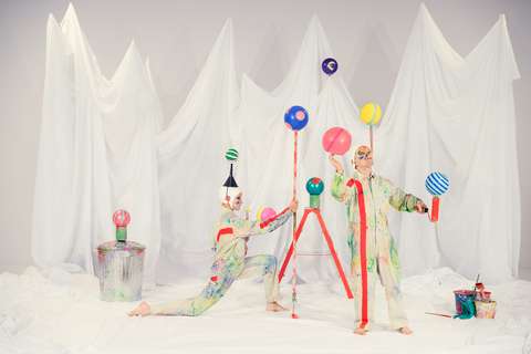 Taitelijat pallojen kanssa valkoisen lakanan edessä.