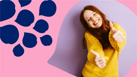 Iloinen ihminen hymyilee kameralle molemmat peukalot pystyssä.