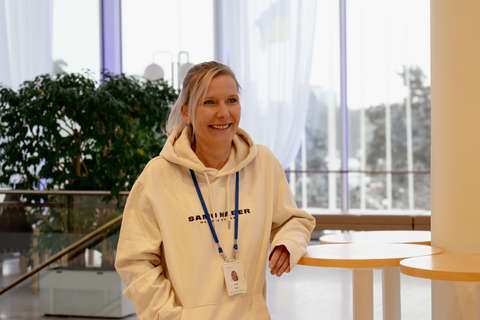 Henkilö hymyilee ikkunan edessä.