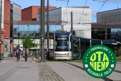 En spårvagn på snabbspårvägslinjen 15 kör förbi metrostationen i Otnäs i sommarstämning. Bilden innehåller en logotyp: Otnäs på en hållbar väg.