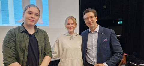 Kuvassa Jussi-Pekka Rantanen ja kaksi lukiolaista hymyilevät kameralle.