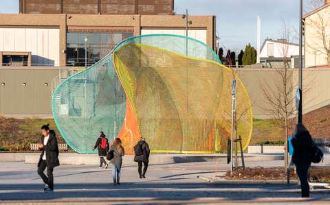 Värikäs julkinen teos katukuvassa, ihmisiä edustalla.