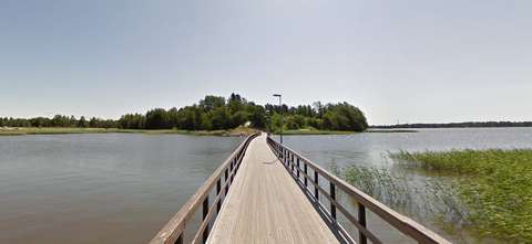 Kuvassa on kapea puinen kevyenliikenteensilta, joka vie kohti Tarvon saarta. 