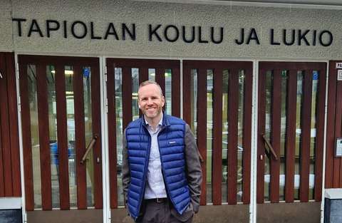 Mika Poutala hymyilee kameralle koulun pääoven edessä.