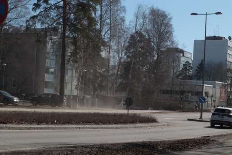 Pölyävä katu, oikeassa reunassa auton perä.