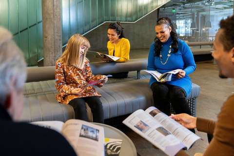 Aikuisia ja lapsia lukemassa julkisessa tilassa.