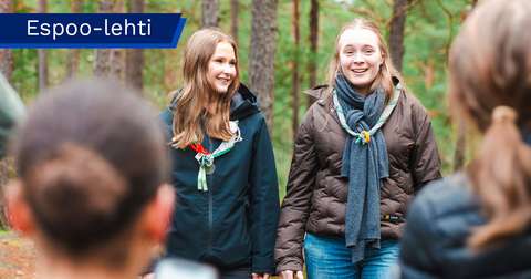 Senja Pitkänen and Kaija Ilomäki in the forest wearing scout scarves around their necks.