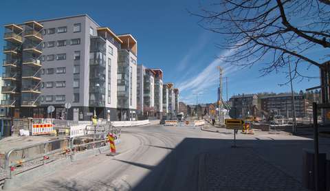 Sininen taivas, kerrostaloja ja katutyömaa.