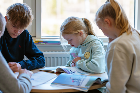 Oppilaat opiskelevat pöydän ääressä.