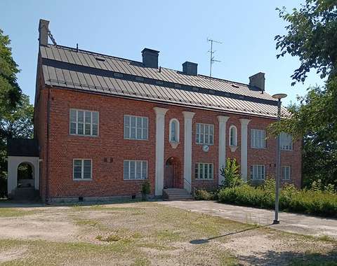 En tvåvåningsbyggnad av rödtegel och med vita detaljer.