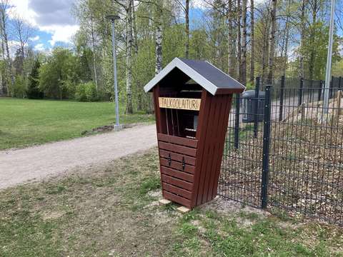 Pieni punainen mökki puistotien laidalla.