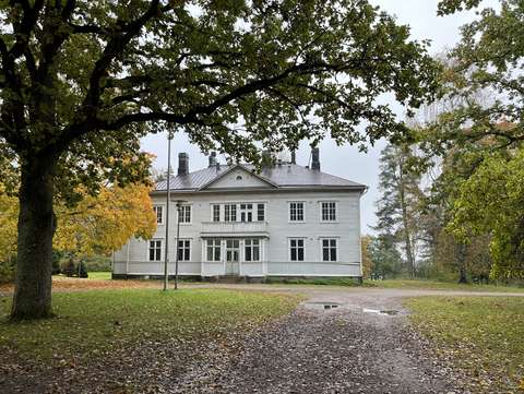 Oittaan kartanon rakennus lehtipuiden reunustamana,