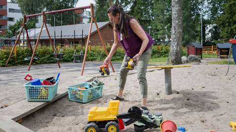 Asukaspuiston ohjaaja Taru Kärhä kokoaa hiekkaleluja säilytyslaatikkoon.