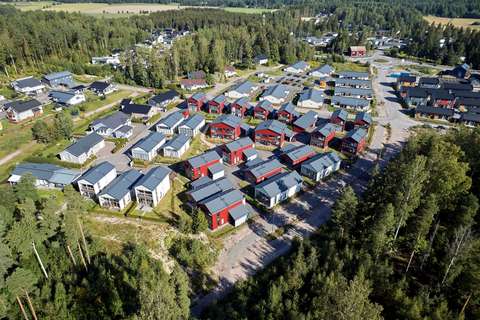 Ilmakuva, jossa näkyy pientaloja, puita, teitä ja peltoja.