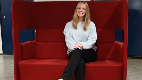 A student is sitting on a red sofa.