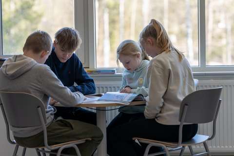 Espoolaiset peruskoulun oppilaat istuvat pöydän ääressä yhdessä.