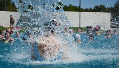 Water splashes around the swimmer in the outdoor pool.