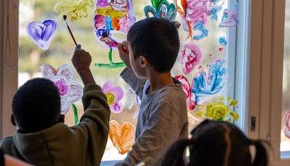 Päiväkodissa lapset maalaavat ikkunaan sormiväreillä taidetta. 