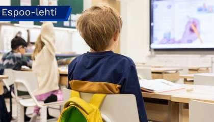 Koululaisia luokkahuoneessa selin kameraan.