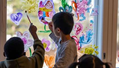 Lapset maalaavat siveltimillä värikkäitä kuvioita ikkunaan.